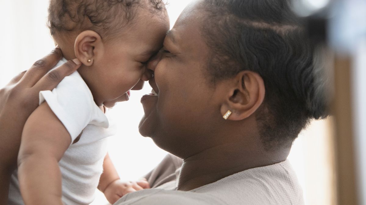 Smiling Black mother kissing baby daughter. Photo Credit Getty Images